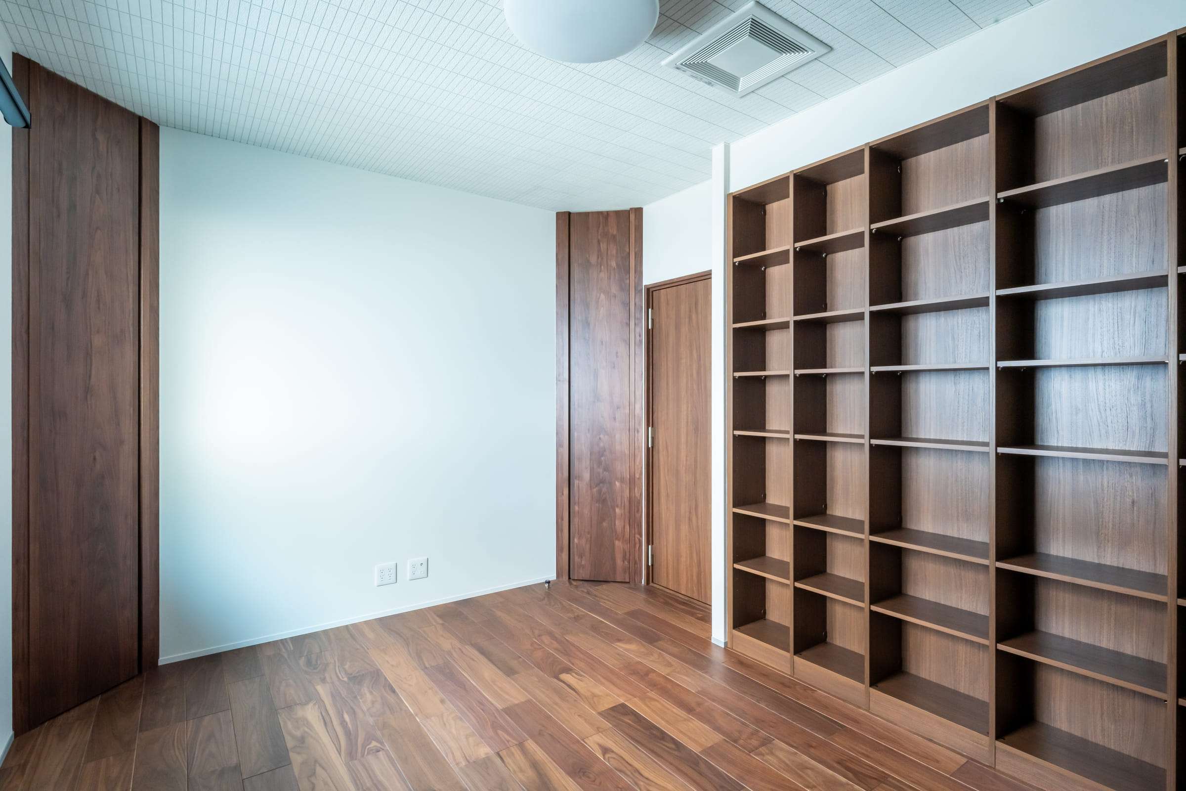 壁一面に造作棚を設けた洋室。無垢フローリングと木の建具