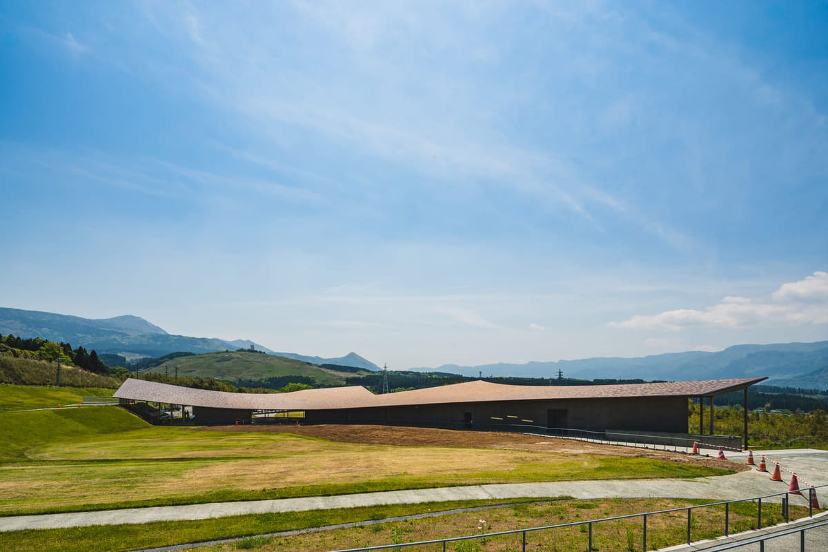 草原の中に横たわる大屋根の建築の遠景