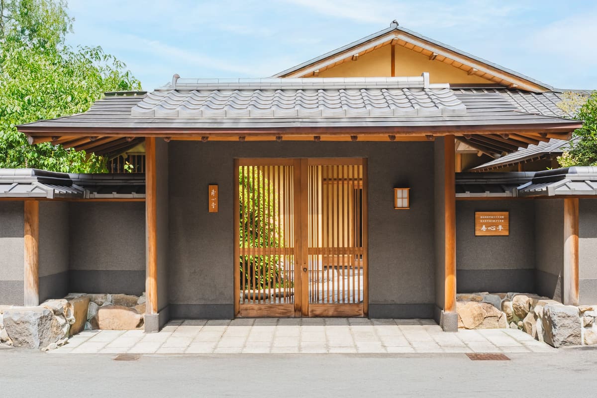 木格子の引き戸を構えた和風施設の玄関。石積みの基礎が回る